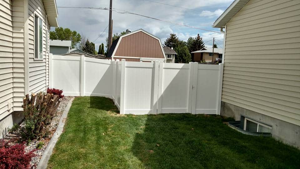 A newly installed white wood fence in a backyard, illustrating how much does a wood fence cost per foot.
