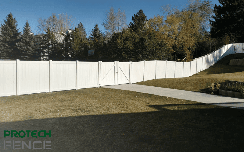  A spacious yard features a pristine white double-panel gate as part of a professional swing gate installation, offering both security and elegance to the property.
