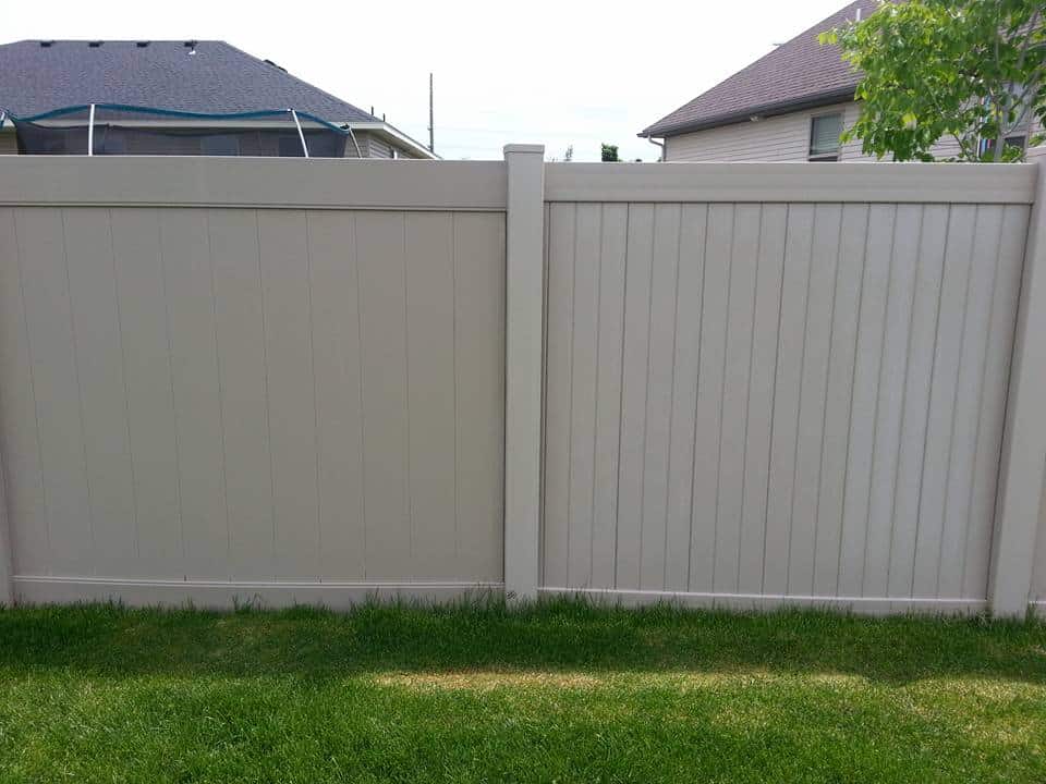 A close-up view of a tall, beige wood fence in a backyard, highlighting how much does a wood fence cost per foot.
