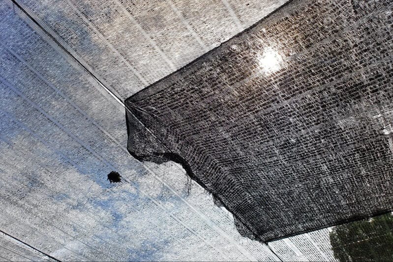 A close-up view of a black mesh fabric used in a shade cloth installation, effectively reducing sunlight exposure and providing UV protection for outdoor spaces.
