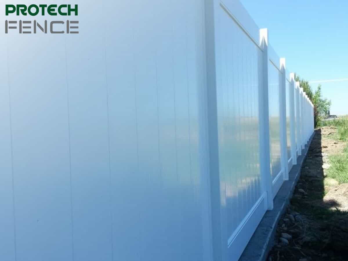 A long stretch of Protech Fence's pristine 10 ft vinyl fence gate running parallel to a rural landscape, showcasing the seamless design and imposing height that ensures privacy and security on the property. 